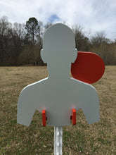 Load image into Gallery viewer, A 11inx13in 3/8in AR500 white and orange steel shooting target with an interlocking swinging paddle and a Studded T-post mount outdoors.