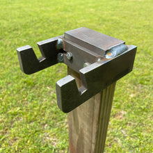 Load image into Gallery viewer, A 3/8" AR500 steel 2x4 mount for reactive hostage shooting targets, mounted on a wooden 2x4 post outdoors with a grassy background.