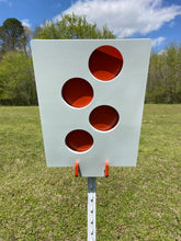 Load image into Gallery viewer, A 12inx18in 3/8in AR500 white and orange steel shooting target with interlocking swinging paddles and a Studded T-post mount outdoors.