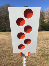 Load image into Gallery viewer, A 12inx24in 3/8in AR500 white and orange steel shooting target with interlocking swinging paddles and a Studded T-post mount outdoors.