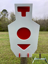 Load image into Gallery viewer, A 12inx24in 3/8in AR500 white and orange steel shooting target with interlocking swinging paddles, accompanied by a 2x4 mount and stand, set outdoors.
