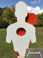 A 12inx21in 3/8in AR500 white and orange steel shooting target with interlocking swinging paddles, accompanied by a 2x4 mount and stand, set outdoors.