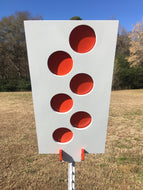 A 12inx24in 3/8in AR500 white and orange steel shooting target with interlocking swinging paddles and a Studded T-post mount outdoors.