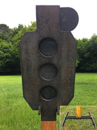 A 10.5inx24in 3/8in AR500 white and orange steel shooting target with interlocking swinging paddles, accompanied by a 2x4 mount and stand, set outdoors.